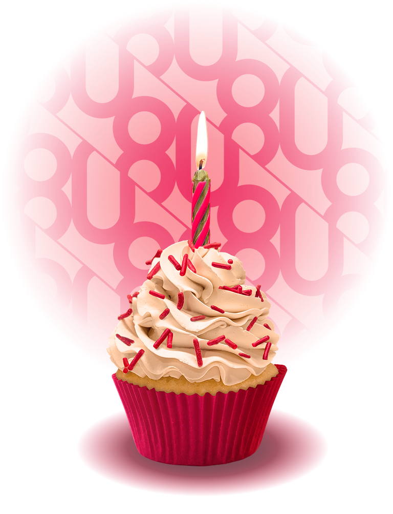 A cupcake with red sprinkles and white frosting with a lit birthday candle on top.